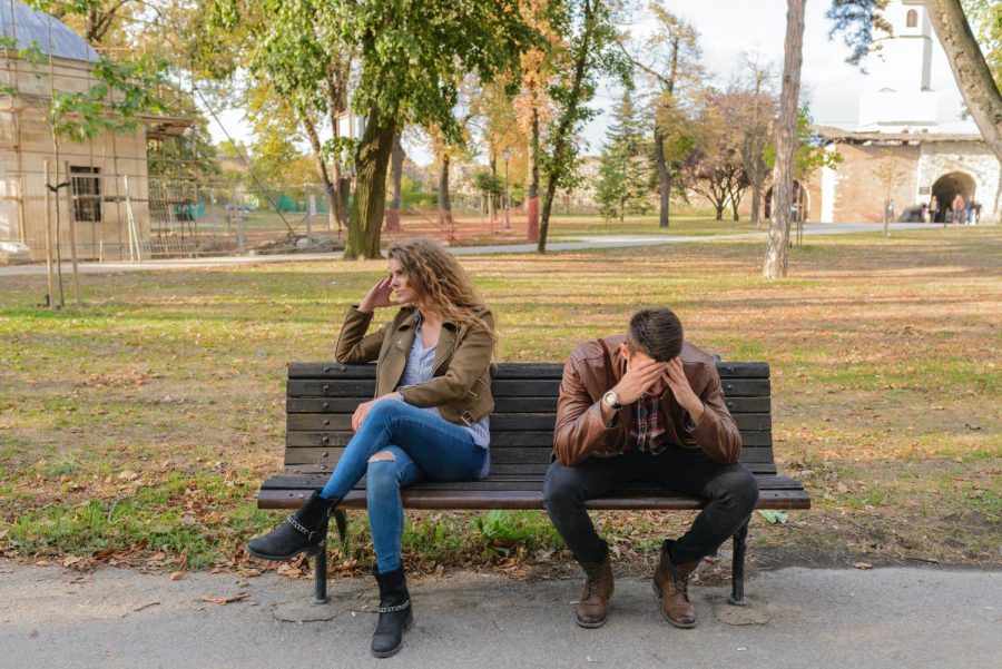 Stressed man and disappointed woman sitting on bench