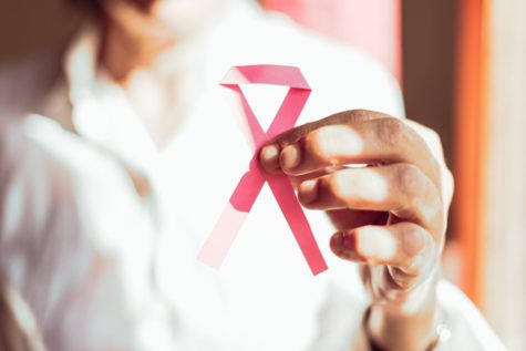 Old person holding up a pink ribbon for breast cancer awareness