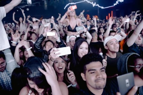 Large crowd of fans recording and cheering at a concert