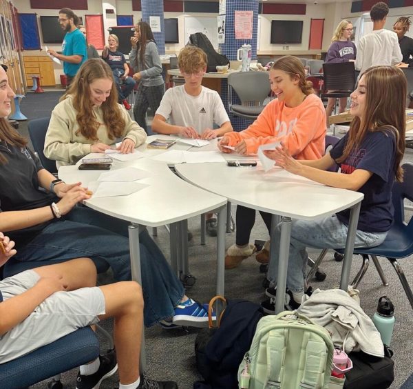 Best Buddies members create paper airplanes.