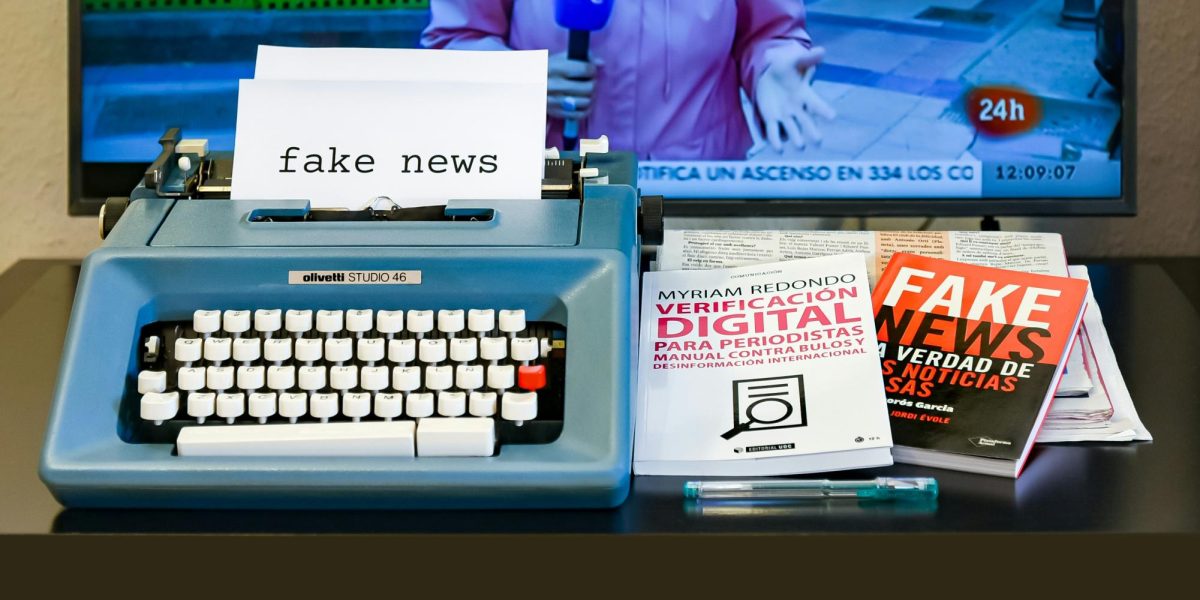  A typewriter with several books on fake news